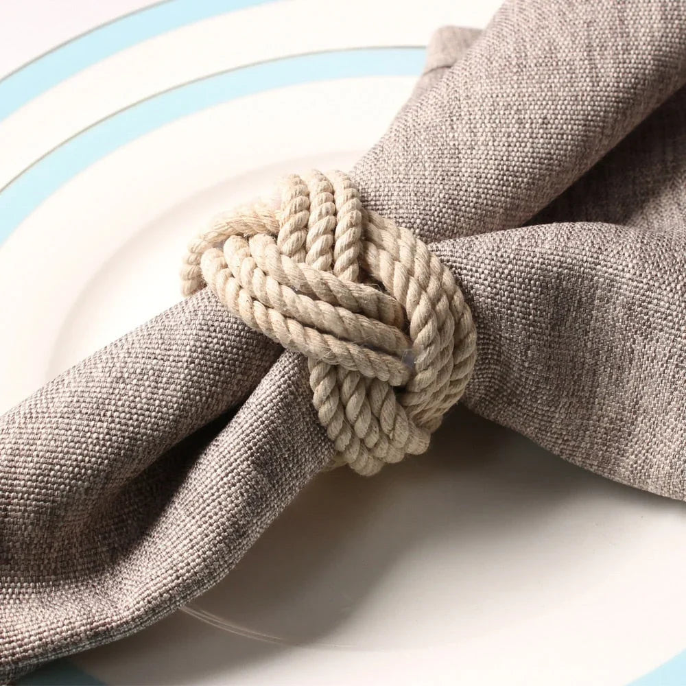 Handgeweven jute servetringen rond opgerolde servetten op een gedekte tafel